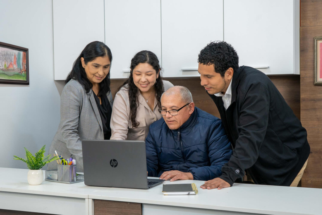 Equipo de Coopac San Miguel reunido frente a una laptop mostrando compromiso y trabajo colaborativo