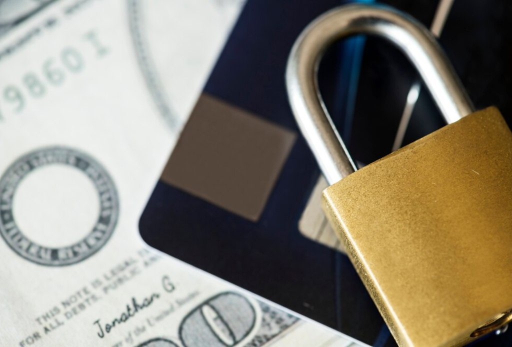 Candado sobre tarjeta y billete simbolizando la protección de datos y la seguridad financiera en Coopac San Miguel
