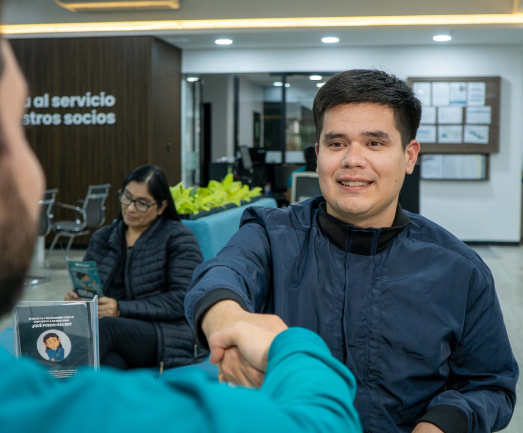 Socio recibiendo atención en agencia Coopac San Miguel, satisfecho tras gestionar su préstamo con depósito a través de Kashio