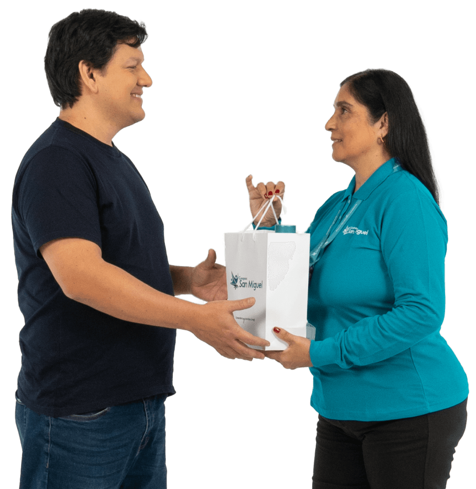 Entrega de obsequio institucional a socio ganador por parte de colaboradora de Coopac San Miguel, ambos sonrientes sosteniendo bolsa con logo de la cooperativa
