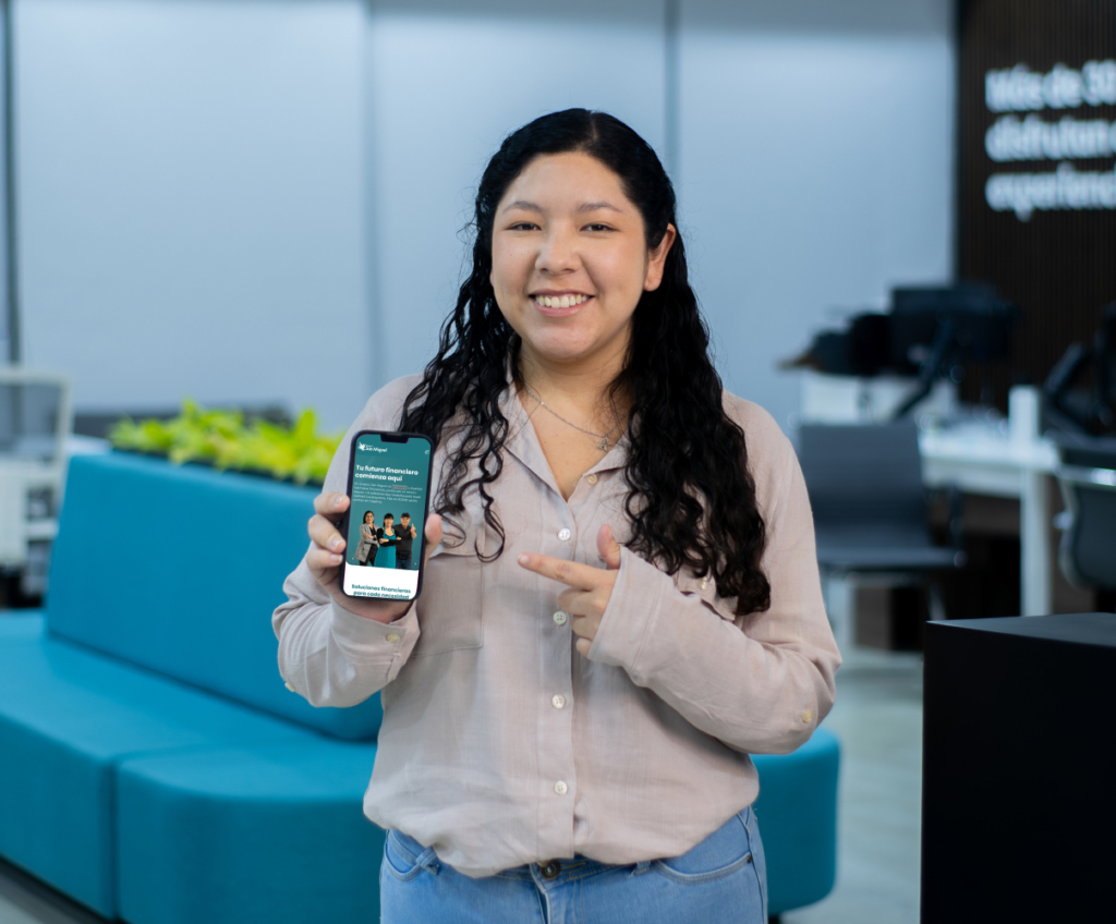 Persona mostrando la app de Coopac San Miguel en su teléfono móvil dentro de una oficina moderna, destacando la facilidad para acceder a servicios financieros